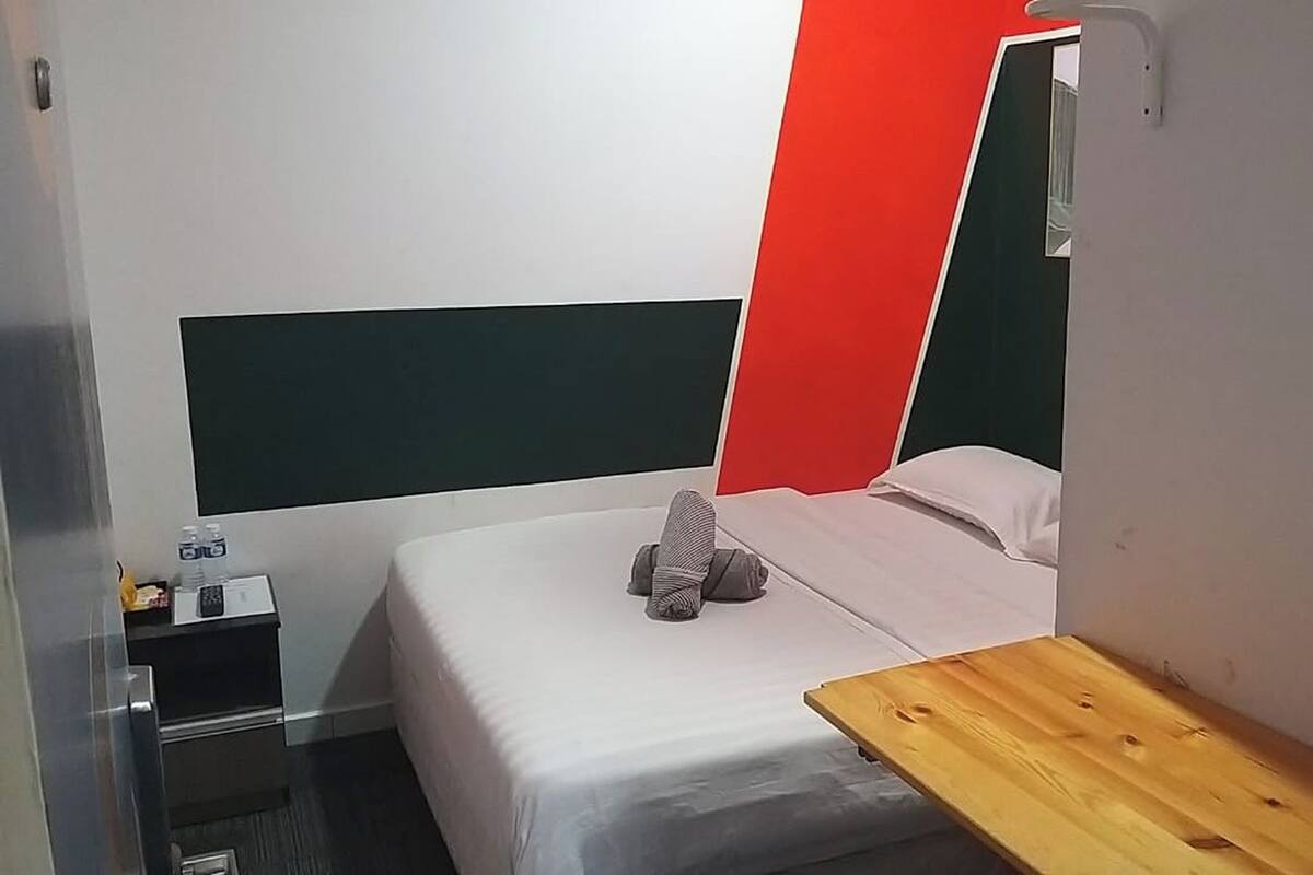 Ein Hotelzimmer mit einem Bett, einem Nachttisch aus Holz, einem kleinen Tisch und einer roten Akzentwand.