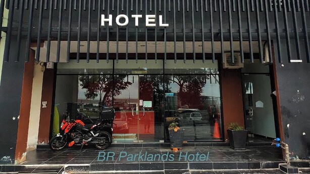 A hotel entrance with a modern design, a motorcycle parked outside, and a sign reading "HOTEL".