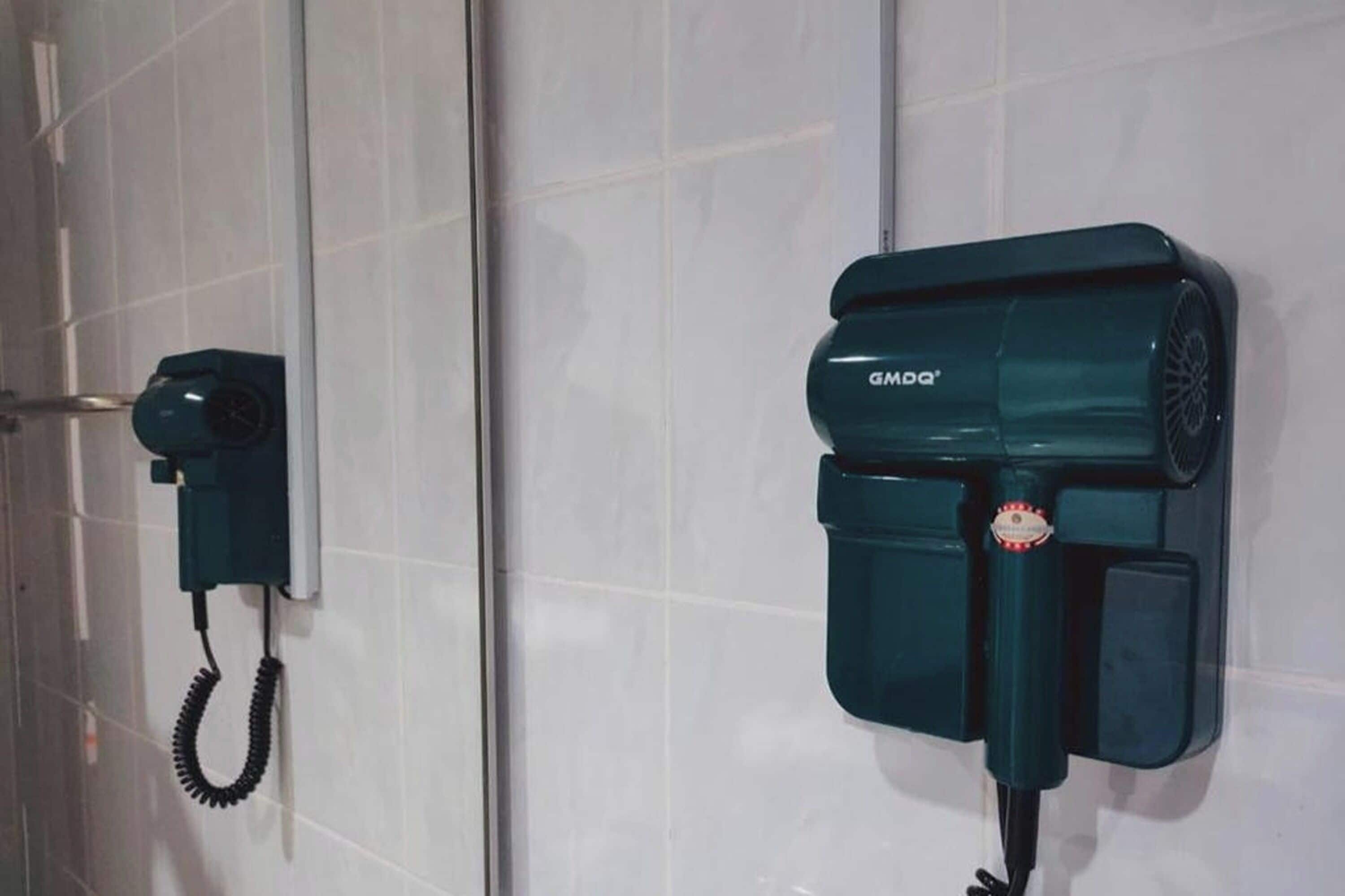 A hair dryer mounted on a white tiled wall.
