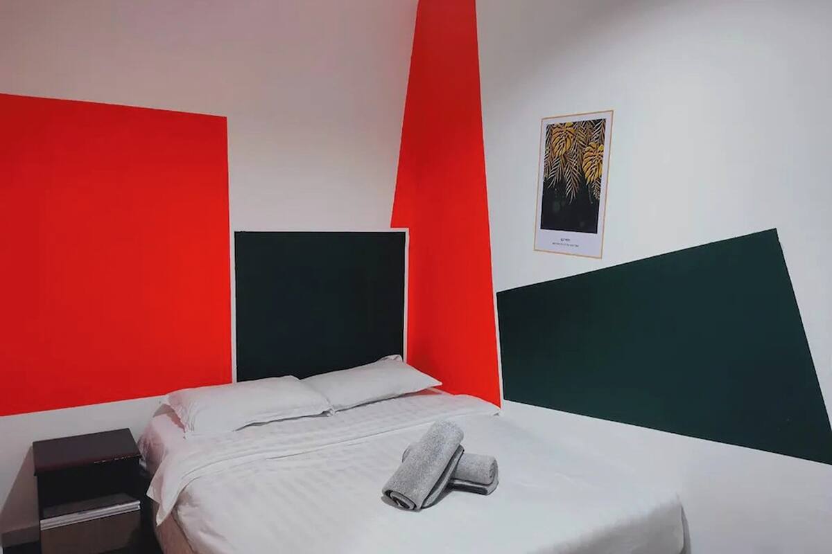 Ein Hotelzimmer mit Bett, weißer Bettwäsche, einem Nachttisch und einem gerahmten Kunstwerk an der Wand.