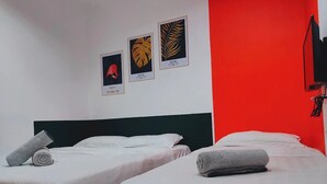 A hotel room with two beds, white bedding, and three framed artworks on the wall.