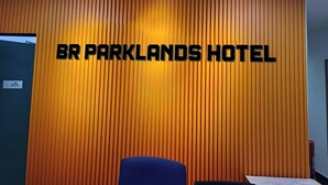 A reception area with a vertical wooden panel wall and a sign that reads "BR PARKLANDS HOTEL".