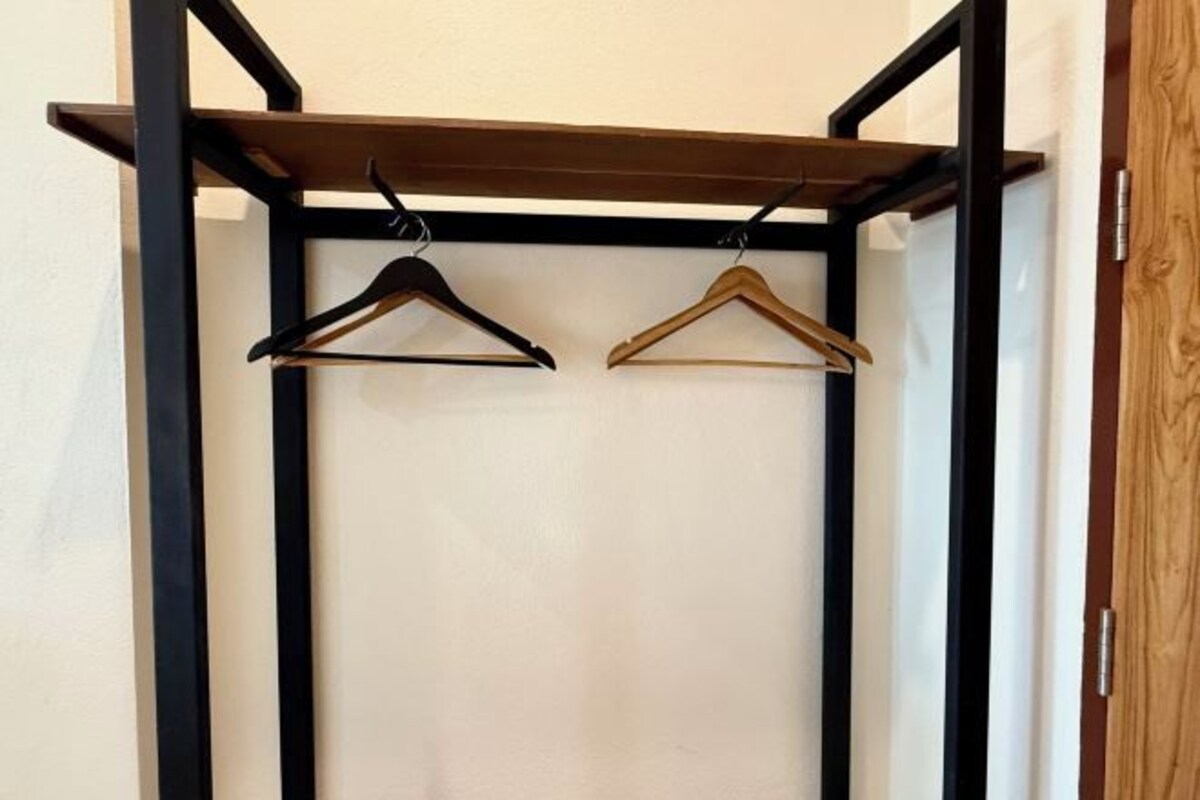 A closet with two wooden hangers and a metal rack.