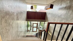 Un escalier avec une rampe en bois et une vue sur l’extérieur, visible à travers une porte vitrée.
