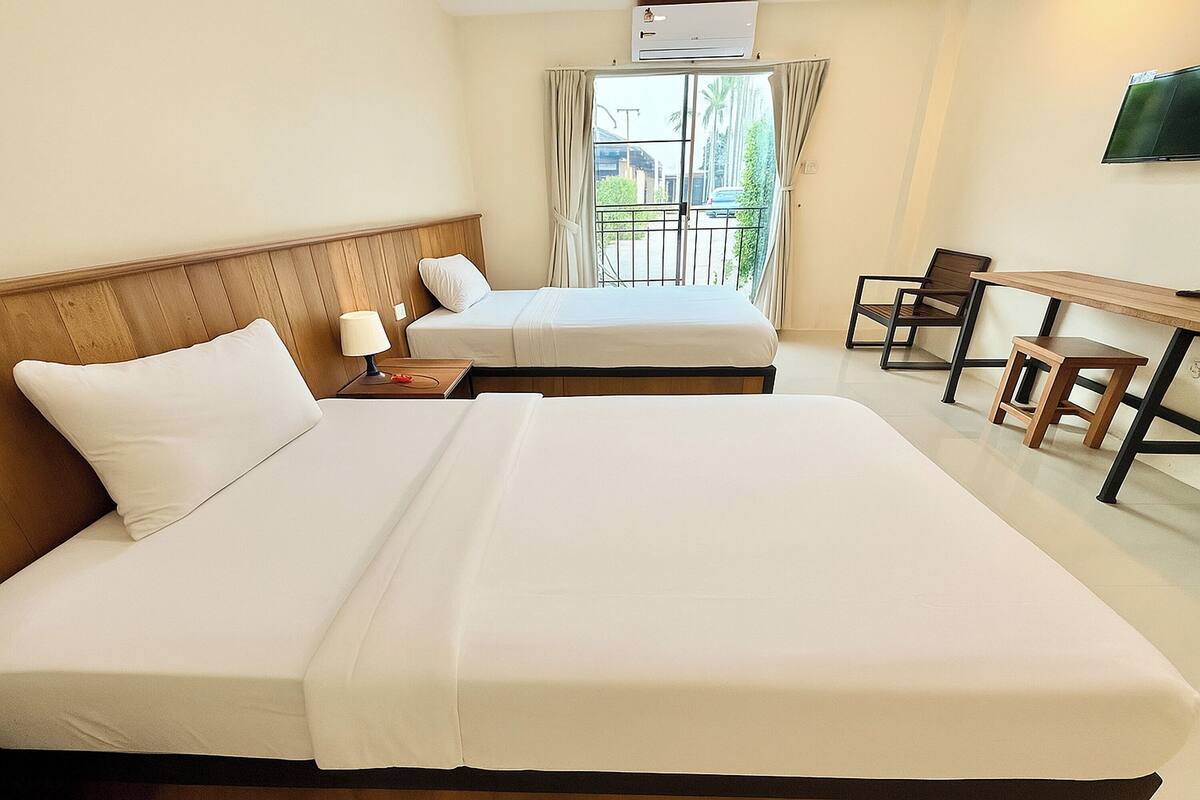 A hotel room with two beds, a desk, a chair, and a TV.