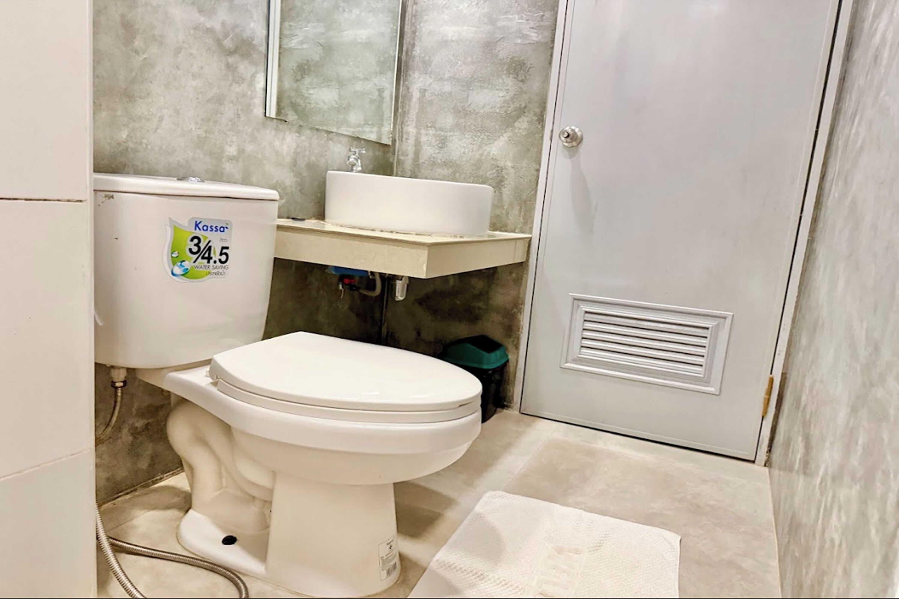 A bathroom with a toilet, a sink, and a water meter.