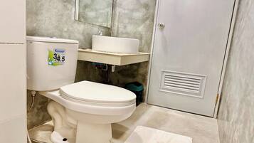 A bathroom with a toilet, a sink, and a water meter.