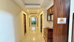 Un couloir d’hôtel avec des portes en bois, un panneau sur le mur de droite et un luminaire au plafond.