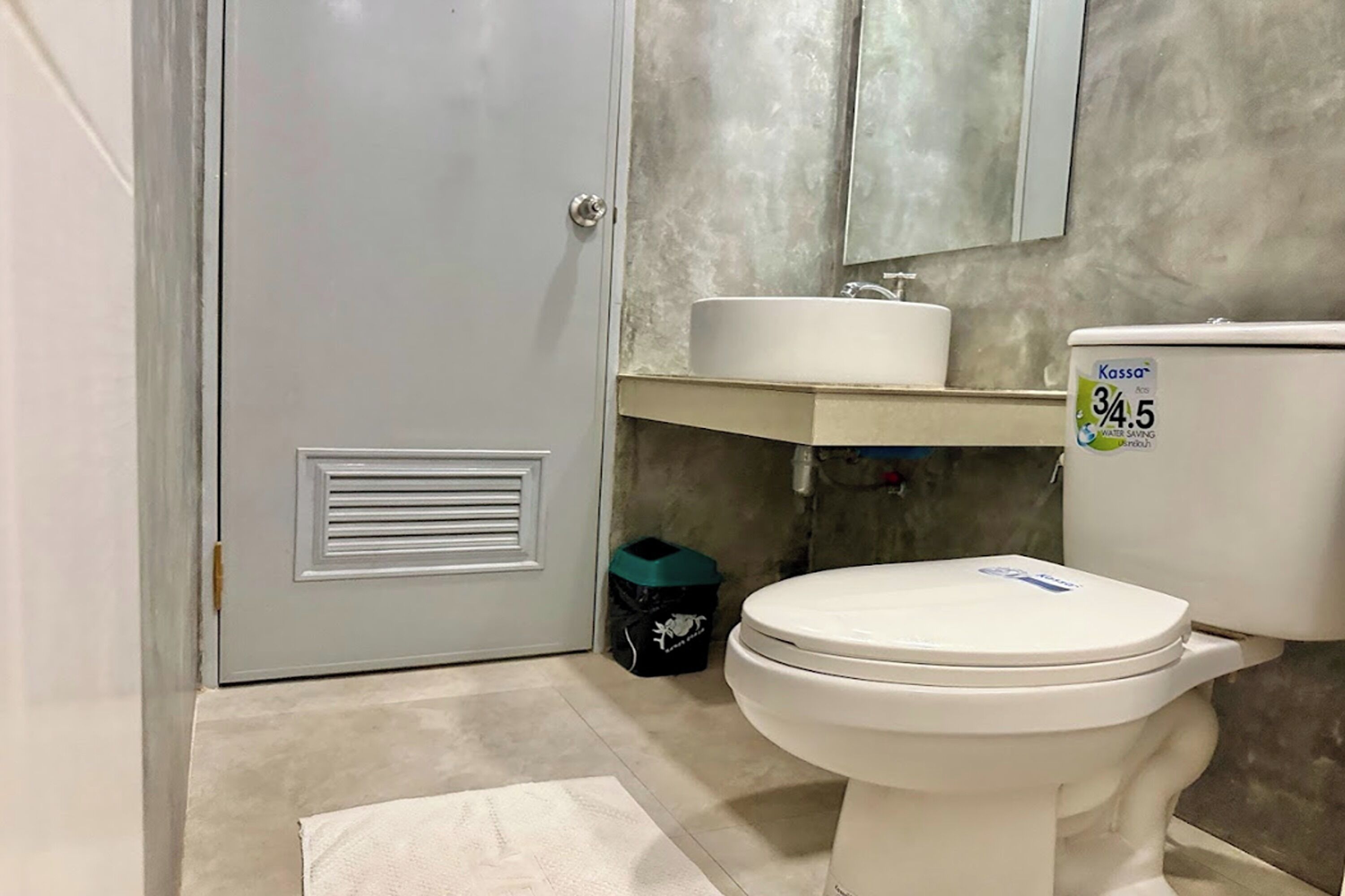 A bathroom with a toilet, a sink, and a mirror.