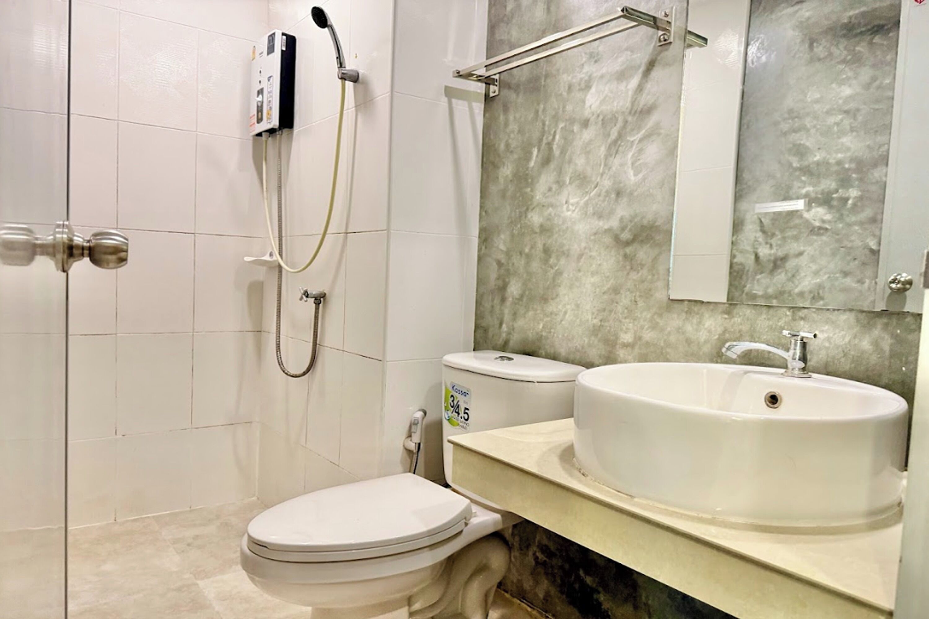 Un baño con inodoro, lavamanos, ducha y espejo.