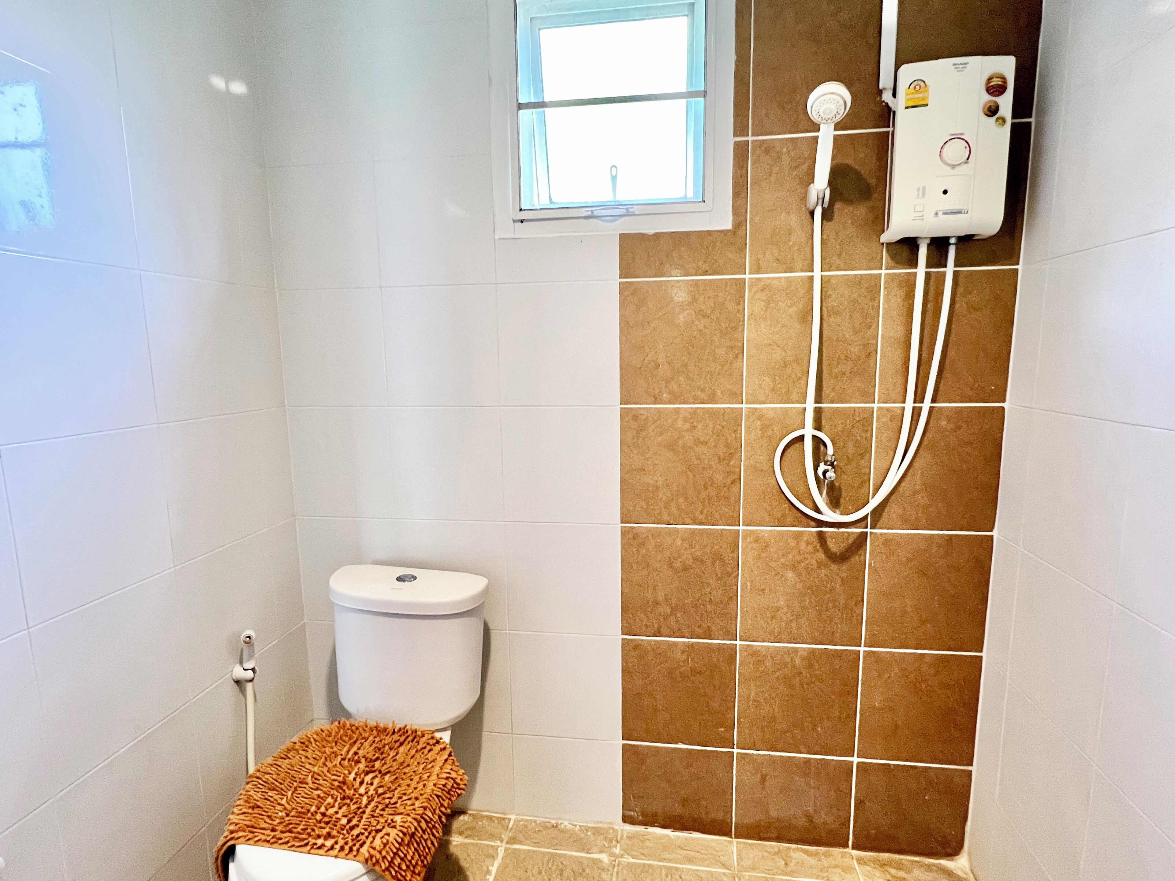 A bathroom with a toilet, a shower, and a window.