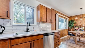 Una cocina moderna con armarios de madera, lavavajillas de acero inoxidable y encimera blanca.