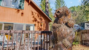 Una cabaña de madera con una gran escultura de oso al frente.