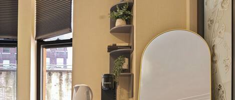 A compact living space with a sofa, a coffee maker, a microwave, and a large mirror.