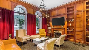 A spacious living room with a fireplace, a television, and a bookshelf. - Chic Two Bedroom Apartment at the Historic Mansfield Residence (New York)