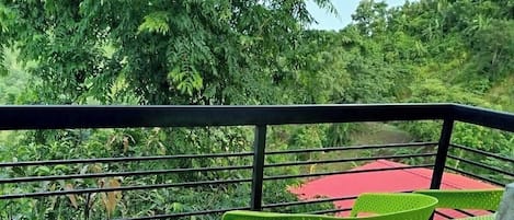 Un balcon agrémenté d’un revêtement de sol vert synthétique, d’une chaise verte et d’une table rouge.
