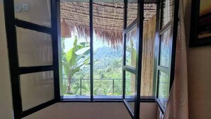 Una habitación con un amplio ventanal que ofrece vistas de un paisaje exuberante con montañas y vegetación.