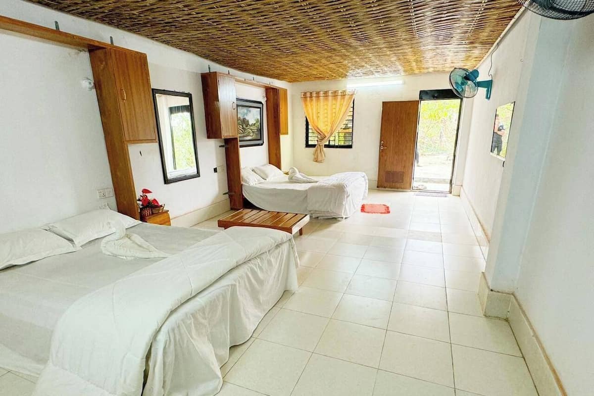 Habitació amb dos llits, sostre de fusta, ventilador i porta que dóna a l'exterior.