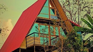 Una casa de dos pisos con techo rojo, ventanas amplias y un balcón.