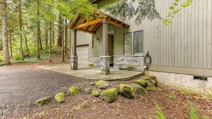 A cabin with a stone foundation, wooden porch, and a covered entryway. - Cozy Riverfront Retreat w/ Hot Tub (Rhododendron)