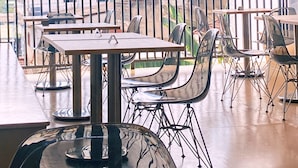 Un espace extérieur aménagé pour les repas, avec des tables et des chaises, offrant une vue sur un château d’eau et des collines en arrière-plan.