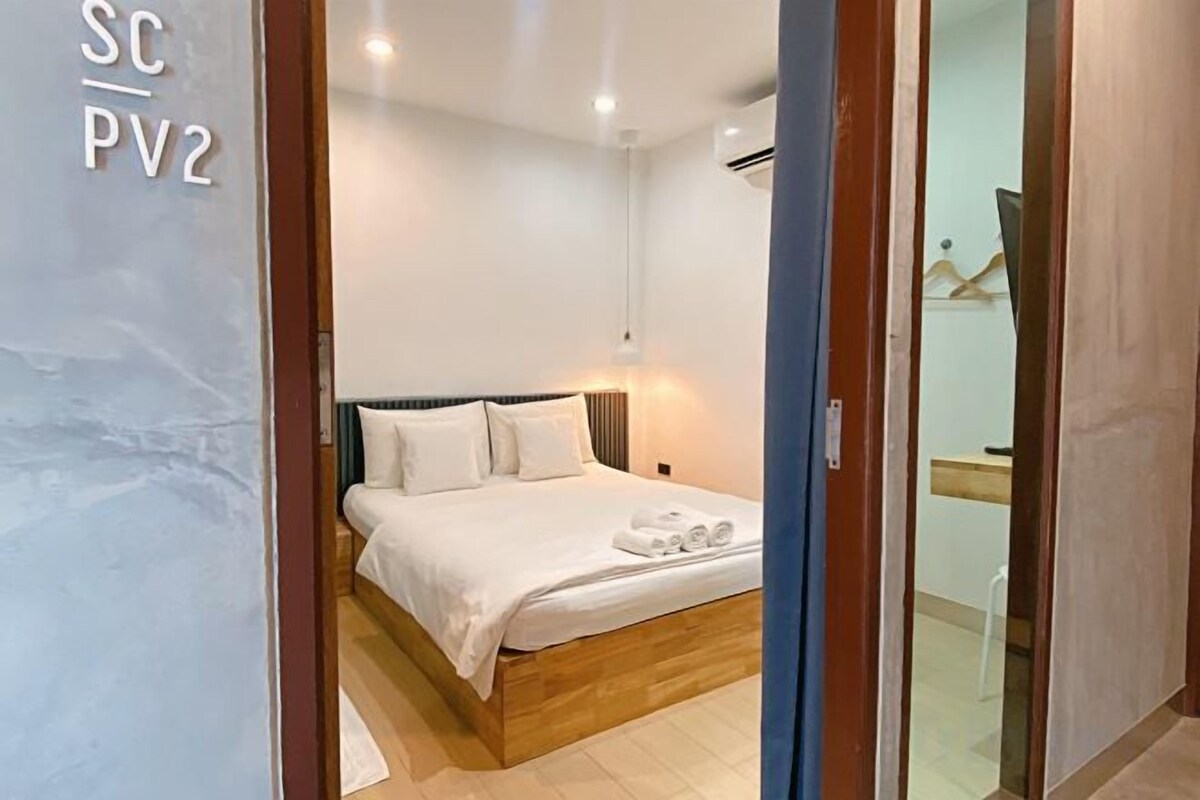 Een slaapkamer met een bed, nachtkastje en een wandairconditioner.