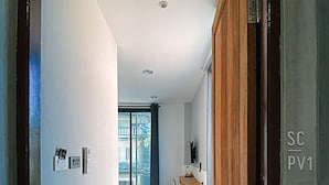 Un couloir moderne avec une porte en bois, un petit coin salon et une vue sur un balcon.