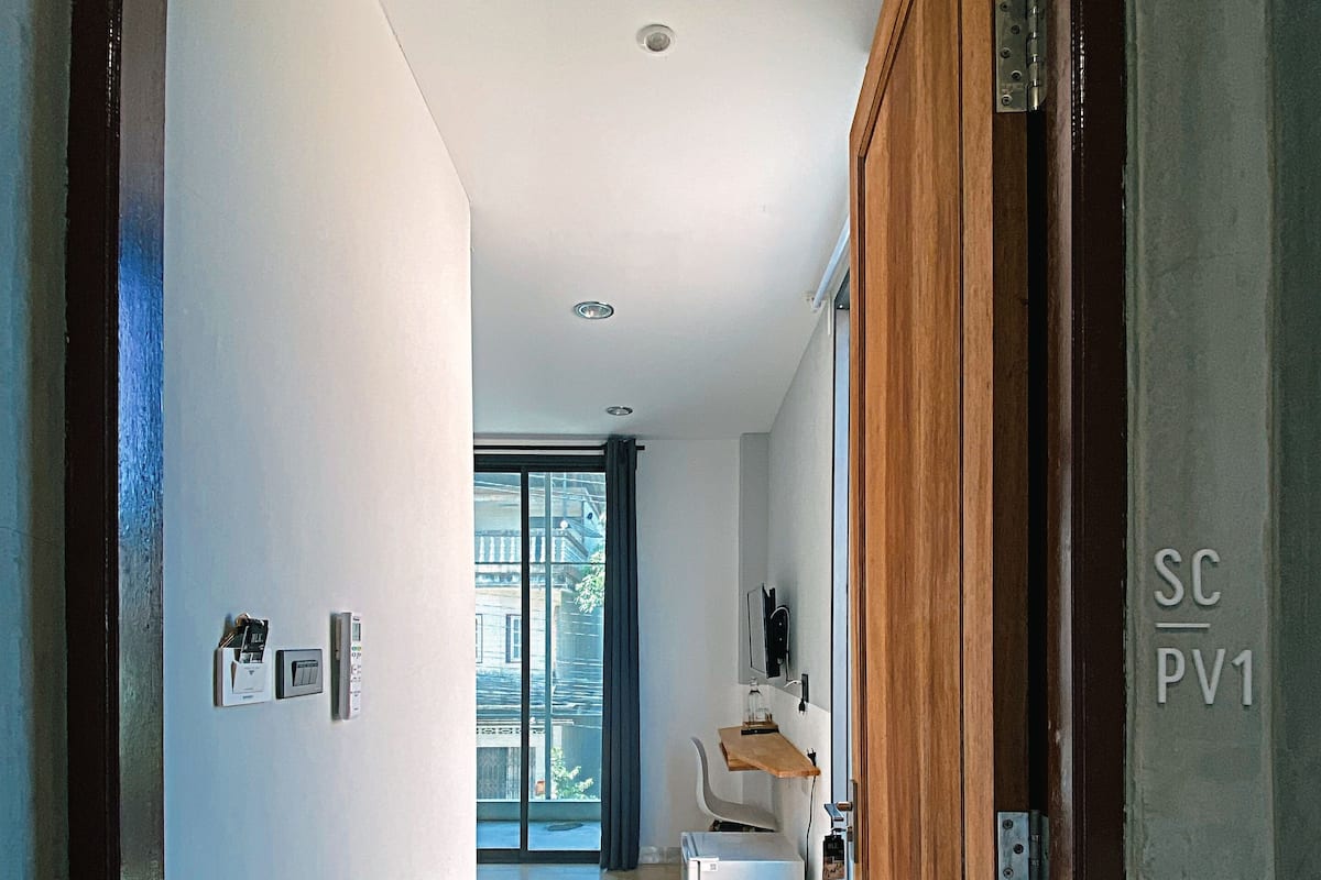 A modern hallway with a wooden door, a small seating area, and a view to a balcony.