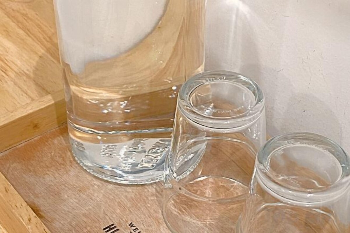 A wooden surface with a large clear glass container and three smaller clear glass containers.