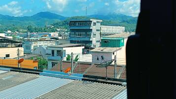 A view of a cityscape with buildings, a prominent multi-story structure, and a mountainous backdrop.