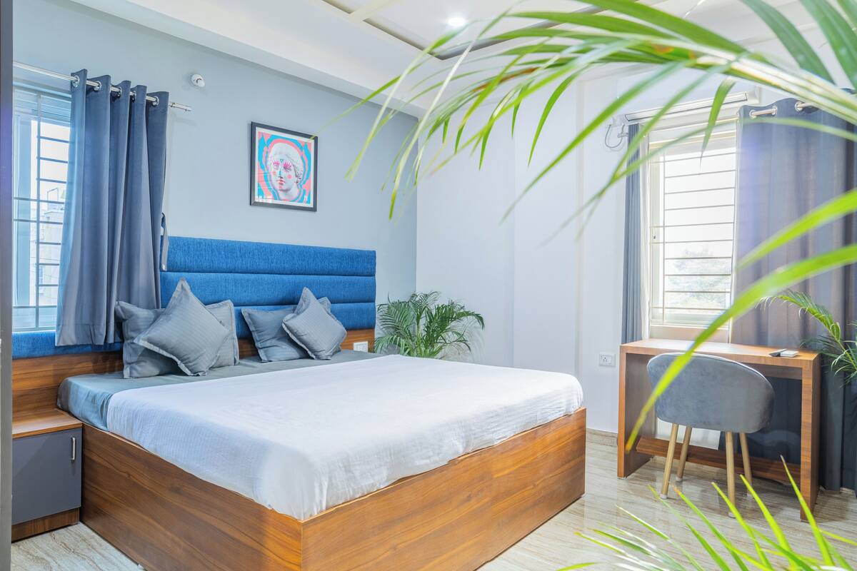 Quarto moderno com cama de madeira, escrivaninha e cadeira.