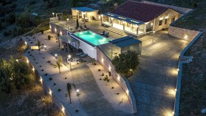 Une maison moderne dotée d’une piscine, d’un espace salon extérieur et de murs en pierre.