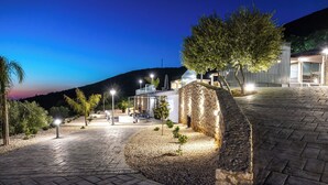Un espace extérieur bien éclairé, doté d’un mur en pierre, d’un chemin et d’un coin salon avec une table et des chaises.