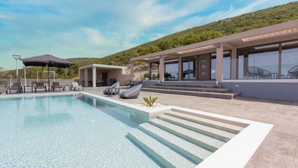 Un espace piscine moderne avec une eau cristalline, des chaises longues et un coin salon abrité.