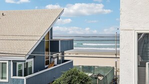 Een gebouw aan de kust met een schuin dak, een balkon en uitzicht op het strand en de zee.