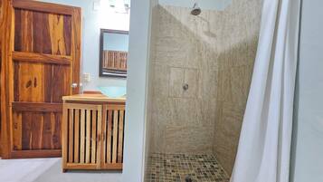 Un baño con un armario de madera, un lavamanos y una ducha con piso de baldosas.