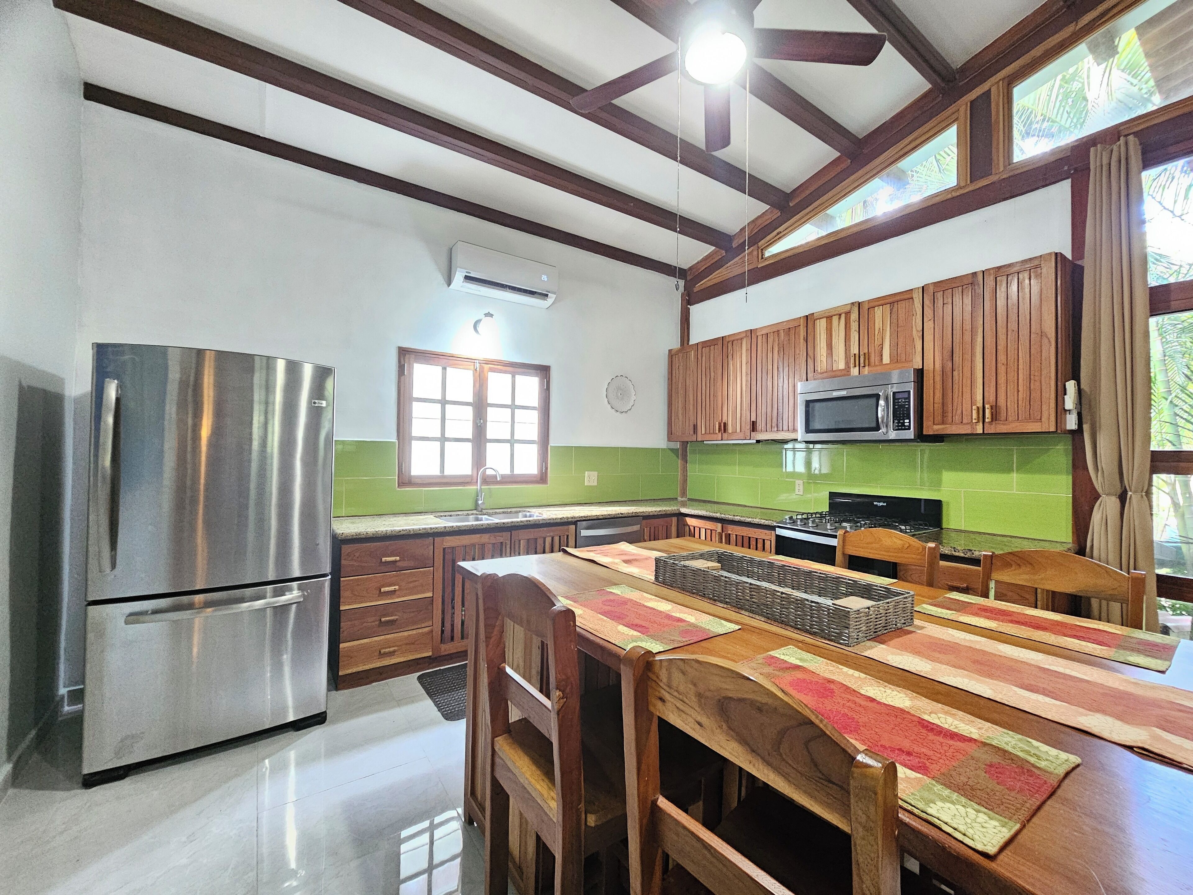 A kitchen with wooden cabinets, a stainless steel refrigerator, a microwave, and a dining table with chairs.