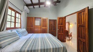 A bedroom with a bed, wooden wardrobe, and a rocking chair. - Pedasi Craftsman Home, Large Screened Deck, Walk to Town (Los Santos Province)