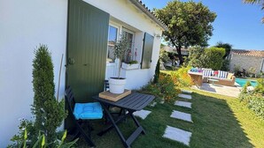 Una casa amb un petit pati, una taula amb una cadira i una planta en test.
