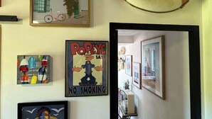 Un passadís amb un salvàvem, un cartell emmarcat que diu "NO SMOKING" i diverses obres d'art emmarcades.