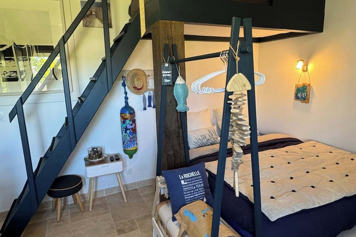 A compact room with a bunk bed, a small desk, and a staircase.