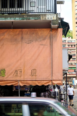 Katukuva, jossa näkyy suuri oranssi markiisi, kyltti, jossa lukee ”Shanghai Street”, ja mies kävelee ohi.