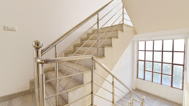 A staircase with metal railings and a view of a window with a grid pattern. - Fabhotel Connect (Jaipur)