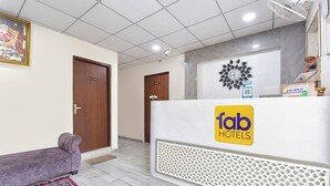 A hotel reception area with a reception desk, a purple sofa, and a patterned rug. - Fabhotel Connect (Jaipur)