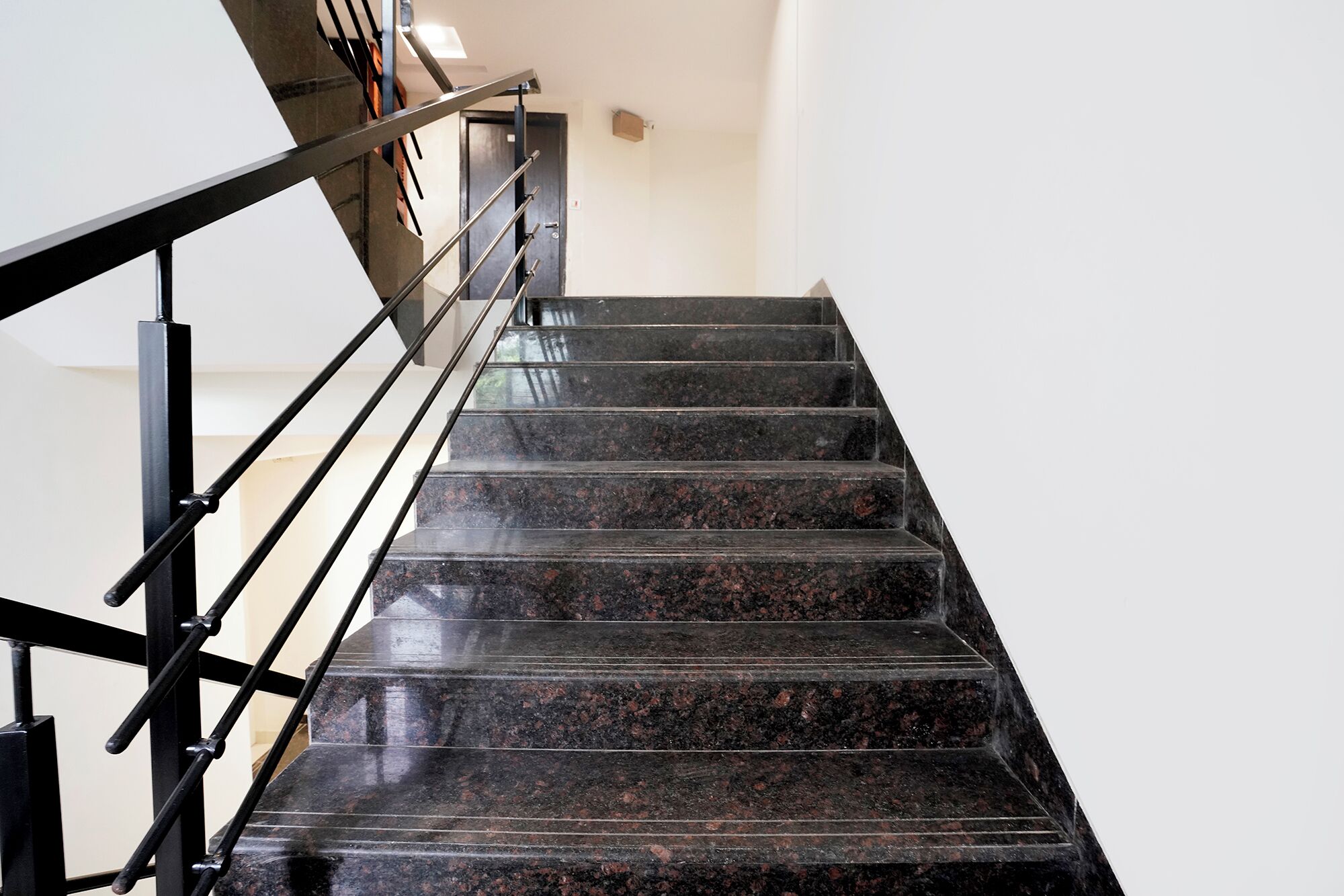 A staircase with black railings and dark granite steps.