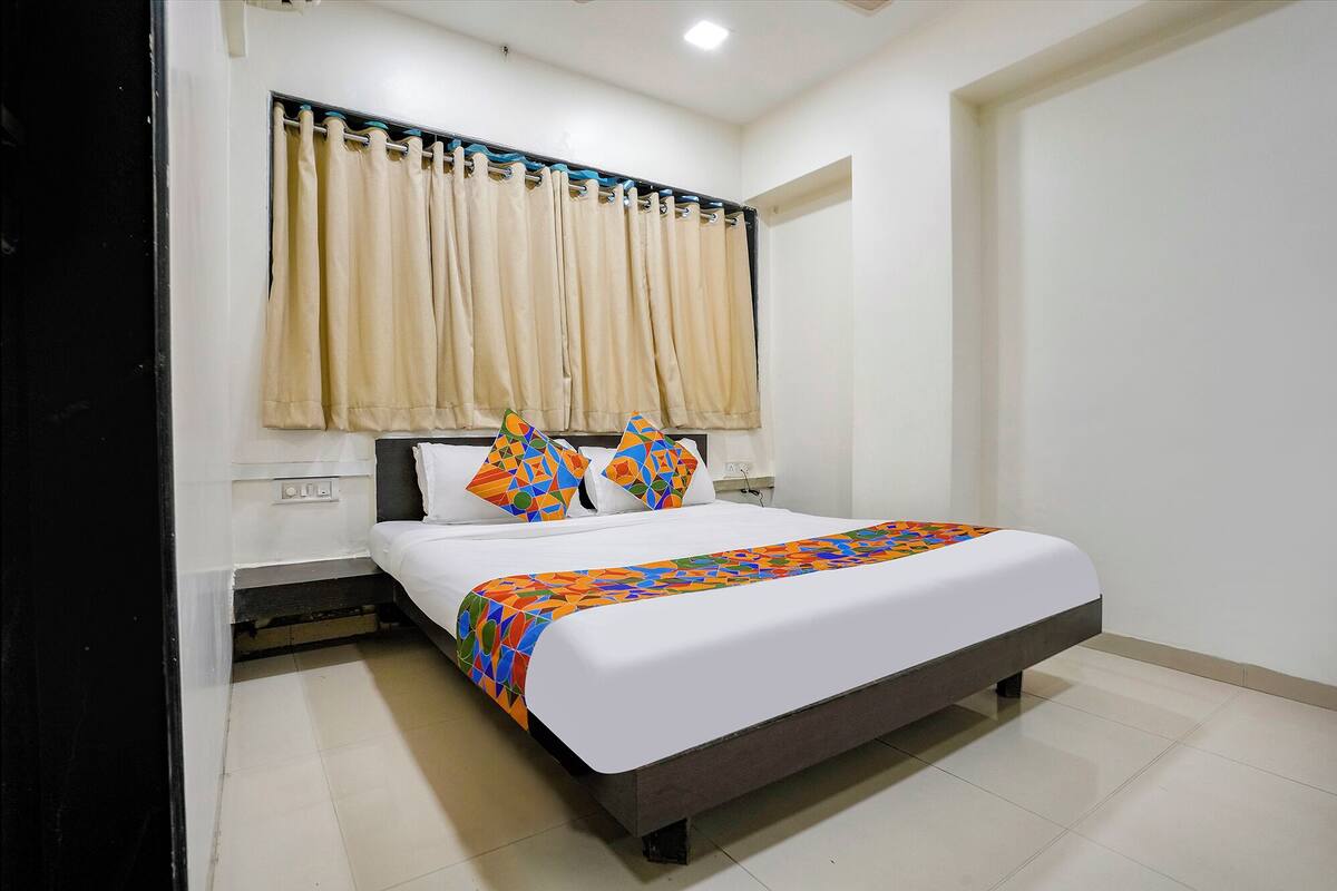 A hotel room with a bed, curtains, and a window.