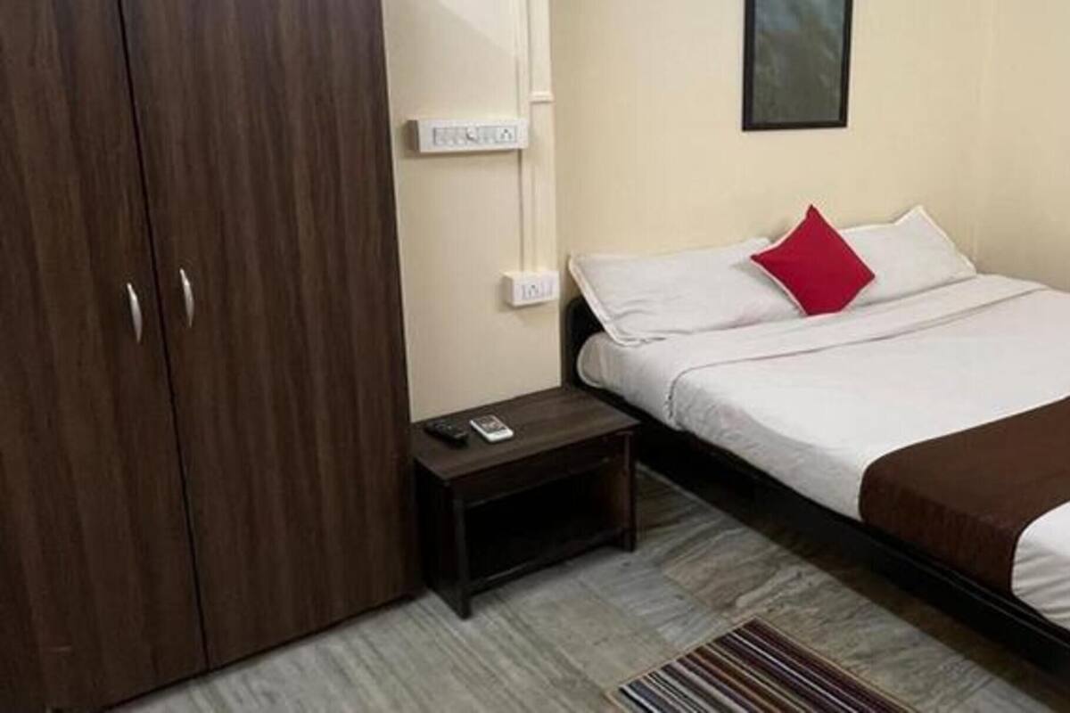 A hotel room with a bed, a nightstand, a wardrobe, and a wall-mounted light switch.