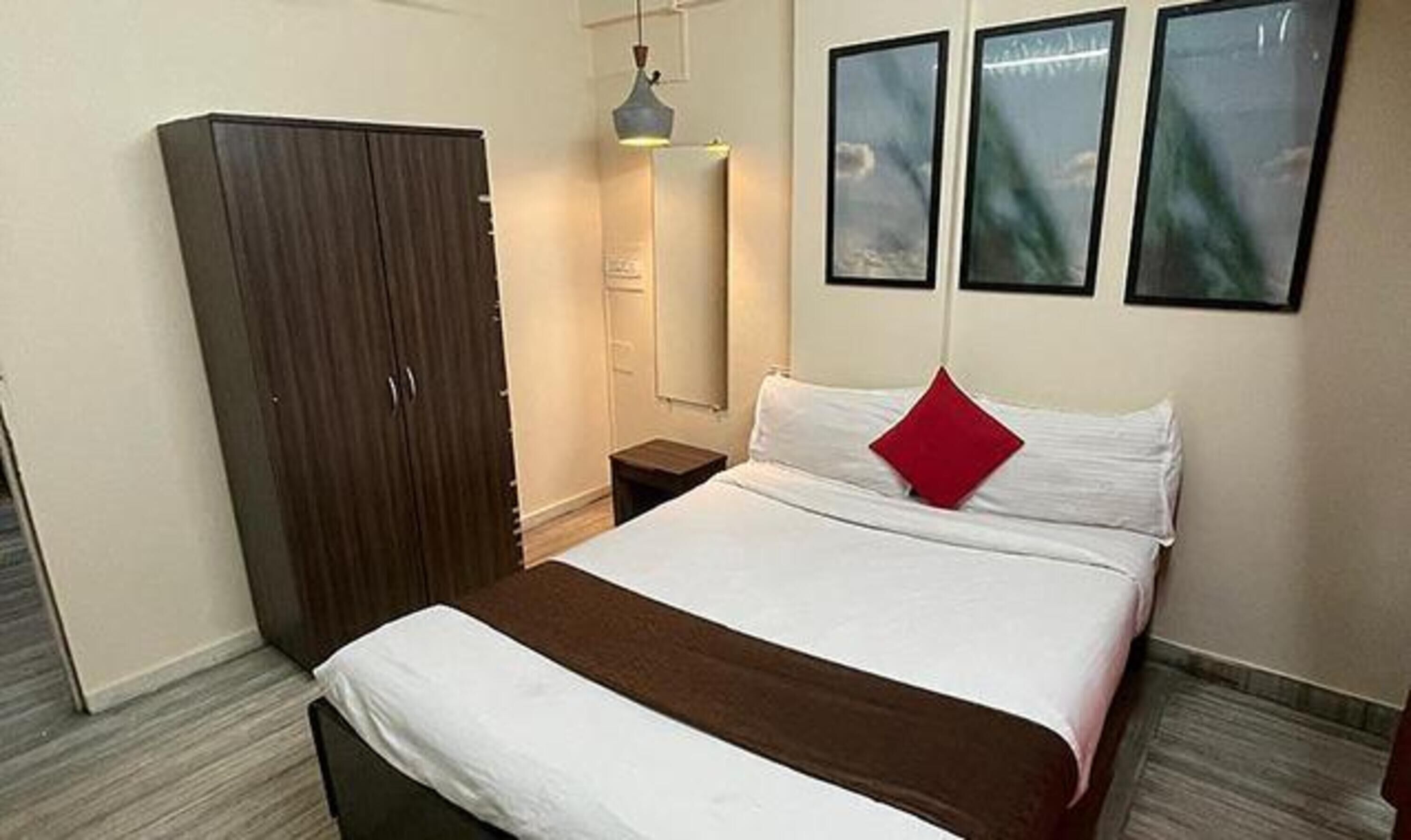 Una habitación de hotel con cama, armario, mesita de noche y lámpara de pared.
