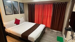 Ein Hotelzimmer mit Bett, Fernseher und Vorhängen.