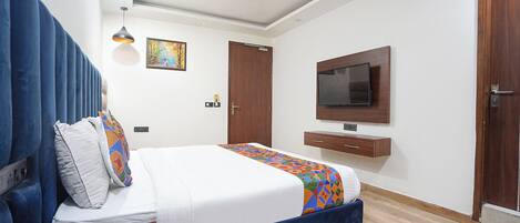 Una habitación de hotel con una cama, un televisor en la pared, un ventilador de techo y una puerta.